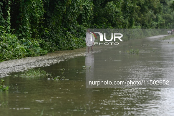 People wade through floodwater in Feni, Chittagong, Bangladesh, on August 23, 2024. 