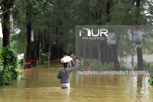 People wade through floodwater in Feni, Chittagong, Bangladesh, on August 23, 2024. 