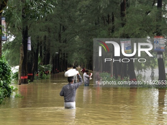 People wade through floodwater in Feni, Chittagong, Bangladesh, on August 23, 2024. (