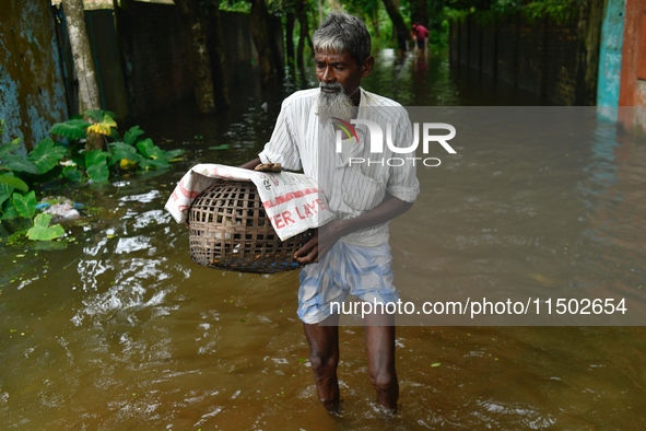 People wade through floodwater in Feni, Chittagong, Bangladesh, on August 23, 2024. 