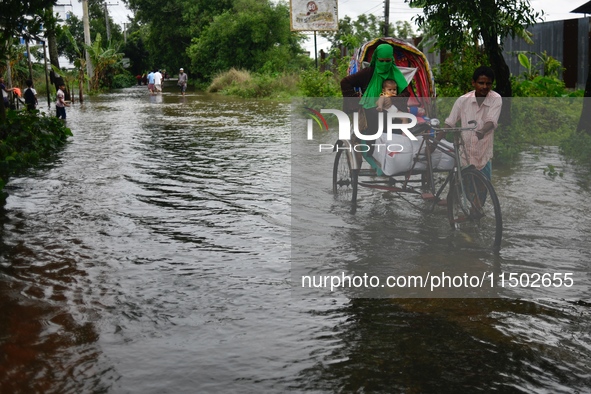 People wade through floodwater in Feni, Chittagong, Bangladesh, on August 23, 2024. 