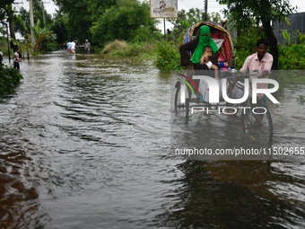 People wade through floodwater in Feni, Chittagong, Bangladesh, on August 23, 2024. (