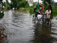 People wade through floodwater in Feni, Chittagong, Bangladesh, on August 23, 2024. (