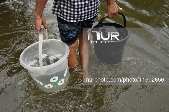 People wade through floodwater in Feni, Chittagong, Bangladesh, on August 23, 2024. 