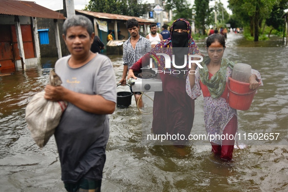 People wade through floodwater in Feni, Chittagong, Bangladesh, on August 23, 2024. 