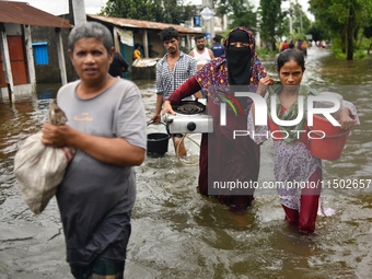 People wade through floodwater in Feni, Chittagong, Bangladesh, on August 23, 2024. (