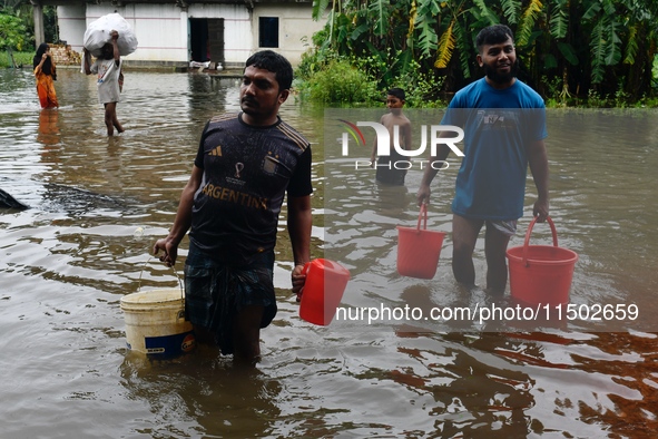 People wade through floodwater in Feni, Chittagong, Bangladesh, on August 23, 2024. 