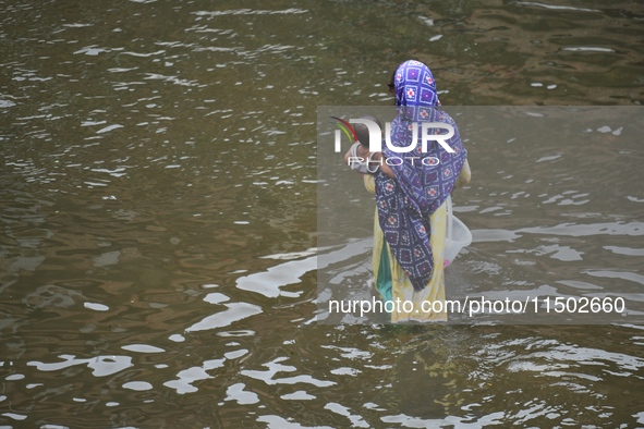 People wade through floodwater in Feni, Chittagong, Bangladesh, on August 23, 2024. 