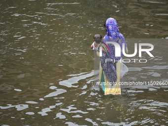 People wade through floodwater in Feni, Chittagong, Bangladesh, on August 23, 2024. (