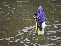 People wade through floodwater in Feni, Chittagong, Bangladesh, on August 23, 2024. (