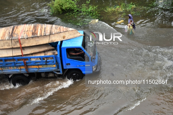 People wade through floodwater in Feni, Chittagong, Bangladesh, on August 23, 2024. 