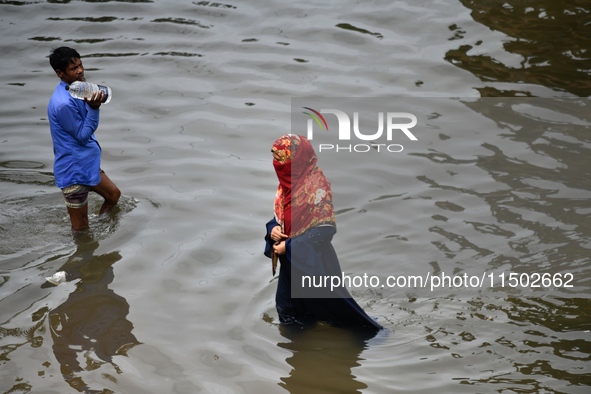 People wade through floodwater in Feni, Chittagong, Bangladesh, on August 23, 2024. 