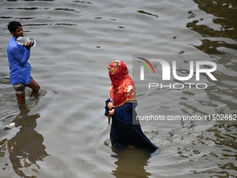 People wade through floodwater in Feni, Chittagong, Bangladesh, on August 23, 2024. (