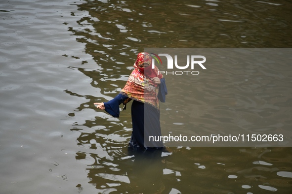 People wade through floodwater in Feni, Chittagong, Bangladesh, on August 23, 2024. 