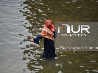 People wade through floodwater in Feni, Chittagong, Bangladesh, on August 23, 2024. (