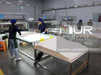 Workers produce reverse osmosis membranes on a production line at the digital intelligent production workshop of Fujian Huameo Environmental...