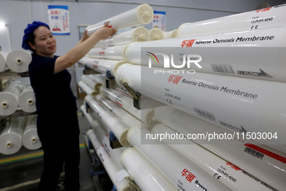 A worker produces reverse osmosis membranes on a production line at the digital intelligent production workshop of Fujian Huameo Environment...