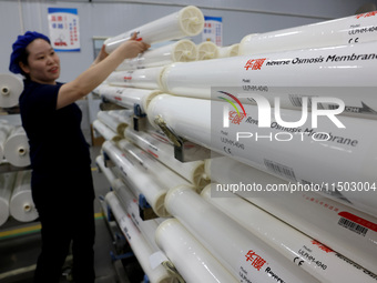 A worker produces reverse osmosis membranes on a production line at the digital intelligent production workshop of Fujian Huameo Environment...