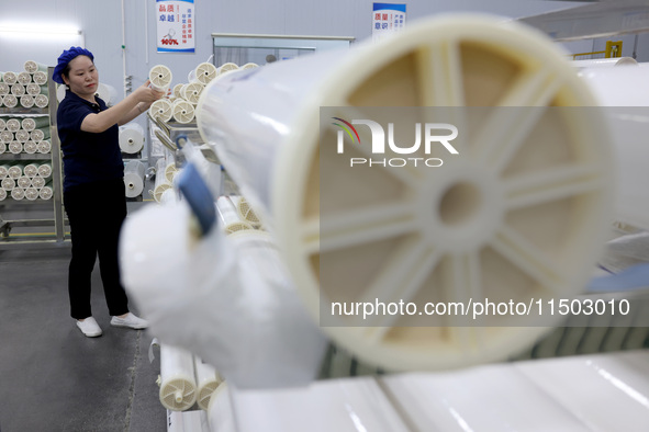 A worker produces reverse osmosis membranes on a production line at the digital intelligent production workshop of Fujian Huameo Environment...