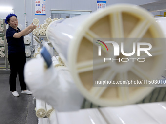 A worker produces reverse osmosis membranes on a production line at the digital intelligent production workshop of Fujian Huameo Environment...