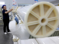 A worker produces reverse osmosis membranes on a production line at the digital intelligent production workshop of Fujian Huameo Environment...