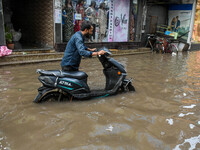 A man navigates his electric scooter through a flooded road caused by heavy rain in Kolkata, India, on August 23, 2024. (