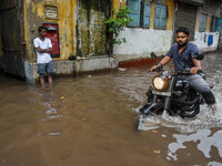 A man rides his bike through a flooded road caused by heavy rain in Kolkata, India, on August 23, 2024. (