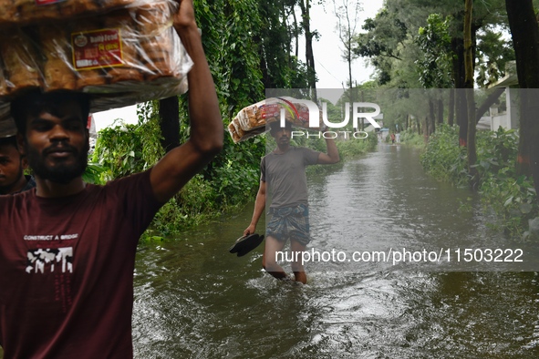 Volunteers carry relief supplies while wading through floodwater in Feni, Chittagong, Bangladesh, on August 23, 2024. 