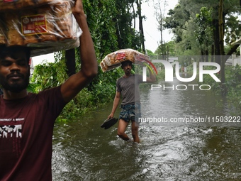 Volunteers carry relief supplies while wading through floodwater in Feni, Chittagong, Bangladesh, on August 23, 2024. (