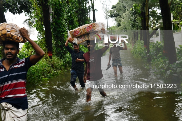 Volunteers carry relief supplies while wading through floodwater in Feni, Chittagong, Bangladesh, on August 23, 2024. 