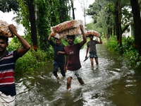 Volunteers carry relief supplies while wading through floodwater in Feni, Chittagong, Bangladesh, on August 23, 2024. (