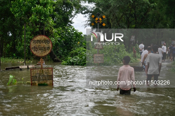 People wade through a submerged rail track due to floodwater in Feni, Chittagong, Bangladesh, on August 23, 2024. 