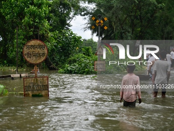 People wade through a submerged rail track due to floodwater in Feni, Chittagong, Bangladesh, on August 23, 2024. (