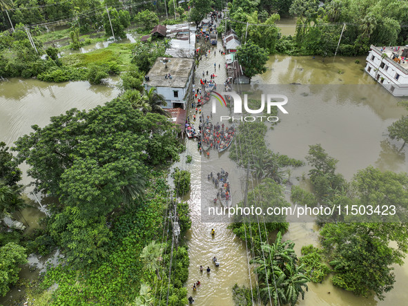 An aerial view shows volunteers rescuing flood-affected residents in the Mohipal area of Feni district in Chittagong division, Bangladesh, o...