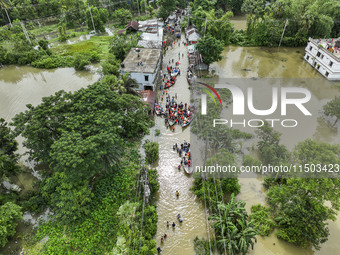 An aerial view shows volunteers rescuing flood-affected residents in the Mohipal area of Feni district in Chittagong division, Bangladesh, o...