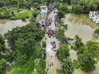 An aerial view shows volunteers rescuing flood-affected residents in the Mohipal area of Feni district in Chittagong division, Bangladesh, o...