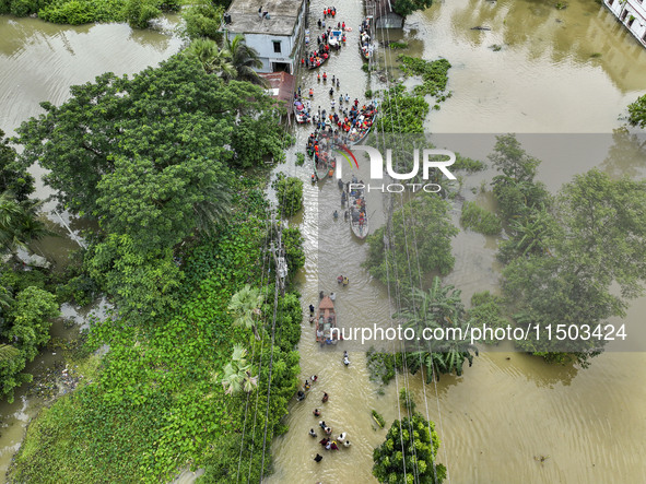 An aerial view shows volunteers rescuing flood-affected residents in the Mohipal area of Feni district in Chittagong division, Bangladesh, o...