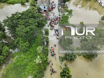 An aerial view shows volunteers rescuing flood-affected residents in the Mohipal area of Feni district in Chittagong division, Bangladesh, o...