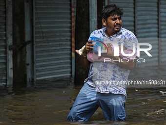 A man with his child wades through floodwaters in the Mohipal area of Feni district in Chittagong division, Bangladesh, on August 23, 2024....