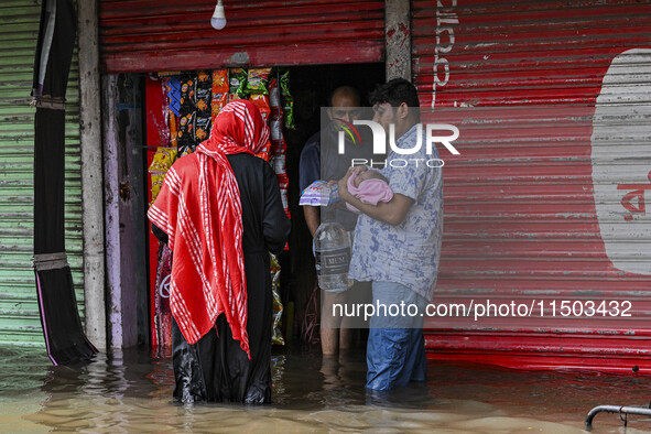 People wade through floodwaters in the Mohipal area of Feni district in Chittagong division, Bangladesh, on August 23, 2024. At least 13 peo...