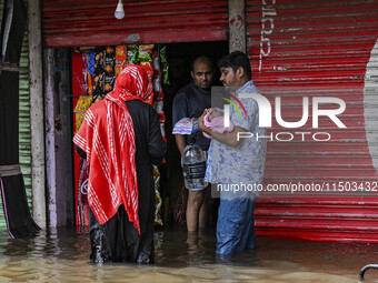 People wade through floodwaters in the Mohipal area of Feni district in Chittagong division, Bangladesh, on August 23, 2024. At least 13 peo...