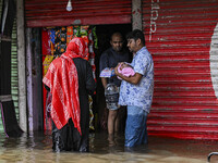 People wade through floodwaters in the Mohipal area of Feni district in Chittagong division, Bangladesh, on August 23, 2024. At least 13 peo...