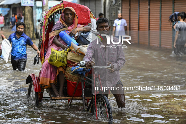 People wade through floodwaters in the Mohipal area of Feni district in Chittagong division, Bangladesh, on August 23, 2024. At least 13 peo...