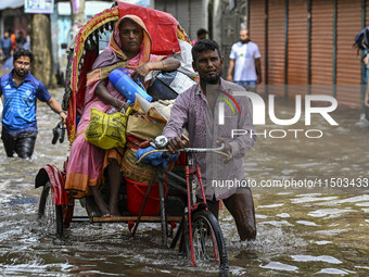 People wade through floodwaters in the Mohipal area of Feni district in Chittagong division, Bangladesh, on August 23, 2024. At least 13 peo...