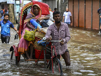 People wade through floodwaters in the Mohipal area of Feni district in Chittagong division, Bangladesh, on August 23, 2024. At least 13 peo...