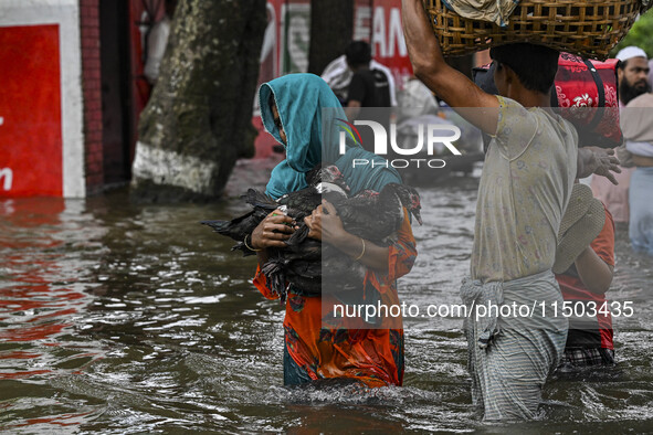 People wade through floodwaters in the Mohipal area of Feni district in Chittagong division, Bangladesh, on August 23, 2024. At least 13 peo...