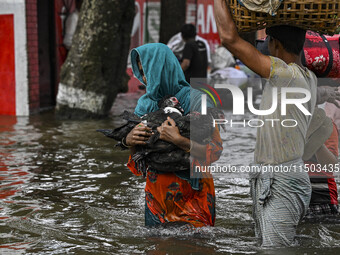 People wade through floodwaters in the Mohipal area of Feni district in Chittagong division, Bangladesh, on August 23, 2024. At least 13 peo...