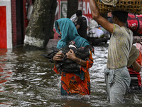 People wade through floodwaters in the Mohipal area of Feni district in Chittagong division, Bangladesh, on August 23, 2024. At least 13 peo...