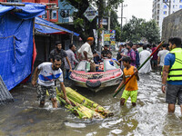 Volunteers use a boat to help rescue people on a flooded street in the Mohipal area of Feni district in Chittagong division, Bangladesh, on...