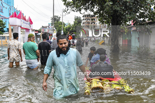 A family uses a raft on a flooded street to take shelter in the shelter house in the Mohipal area of Feni district in Chittagong division, B...